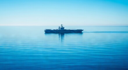 A solitary aircraft carrier glides across the immense, tranquil blue ocean under clear skies. A powerful vessel on an endless sea, military, strategic, simple