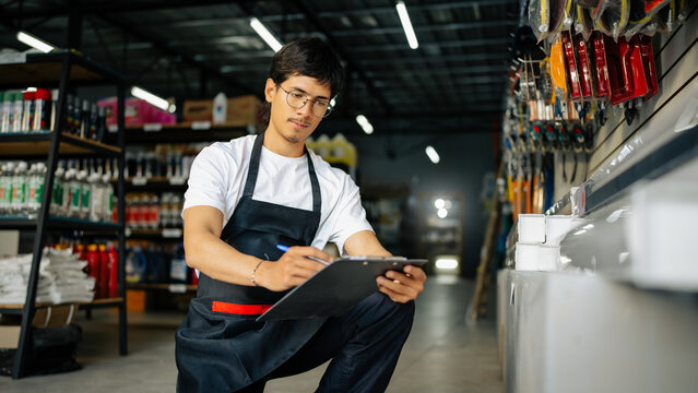 Employee checking stock levels and writing notes in a hardware store