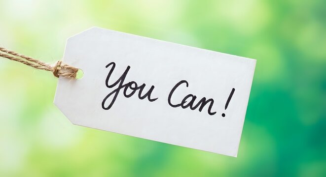White paper tag with You Can motivational message on rope against soft green bokeh background for inspiration and encouragement concepts.