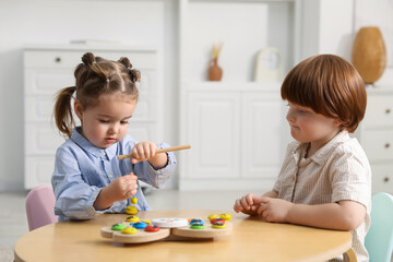 Naklejka premium Cute little children playing with toys at wooden table indoors