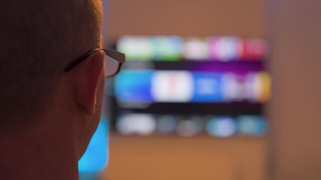 Man watching streaming tv with blurred colorful thumbnails