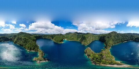 Aerial view of a turquoise lagoon surrounded by dense tropical vegetation. The irregular shape of the water forms small coves and tree-covered peninsulas, creating a striking contrast between the deep © Felipe