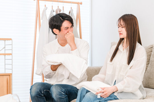A couple folding laundry in the living room (damp, damp smell, drying indoors)