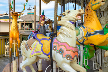 Intricately carved, colorful wooden horses, unicorns, giraffes and reindeer on a carousel merry-go-round along a waterfront boardwalk at Myrtle Beach, South Carolina. © Kirk Fisher