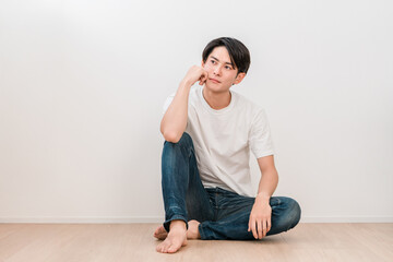 A young Asian man sitting in a living room with white walls (Men's Beauty)