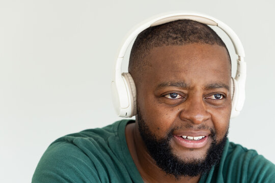 African man wearing white headphones and green crew-neck shirt in studio, looking right, copy space