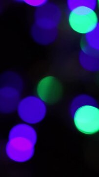 Una toma de cerca de varias luces de colores en forma de c&iacute;rculos en movimiento en la oscuridad. Desenfoque. Video vertical