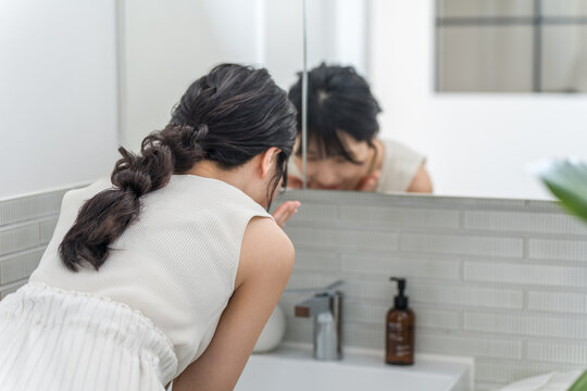 A young Asian woman washing her face in the bathroom (makeup remover, cleanser, foam face wash)