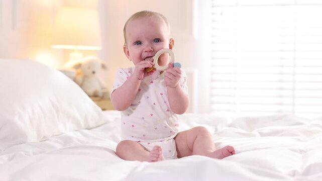 Cute little baby with teether on bed at home