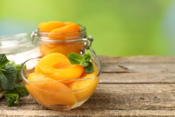 Pickled peaches and mint leaves on wooden table, closeup. Space for text © New Africa