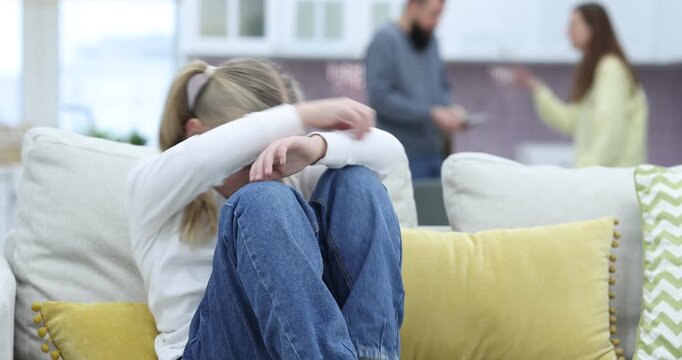 Alimony. Sad little girl sitting on sofa while her parents arguing at home, selective focus