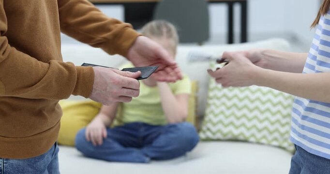 Alimony. Man giving money to ex-wife while his sad daughter sitting on sofa indoors, selective focus