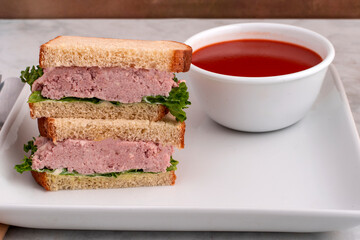 spam salad sandwich  with  a bowl of  tomato soup