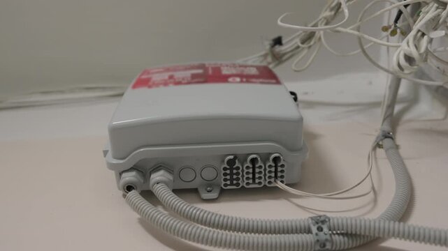 Low Angle View of Fiber Optic Network Distribution Box with Cables and Conduits Mounted on Ceiling in Building | Telecommunications Infrastructure Close-Up