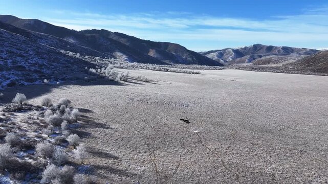 Aerial view of snowy alpine pastures and mountain ranges in Aba, Sichuan, featuring grazing horses and rime on the winter plateau