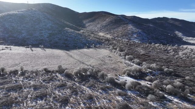 Aerial view of snowy alpine pastures and mountain ranges in Aba, Sichuan, featuring grazing horses and rime on the winter plateau
