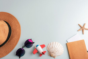 Strow hat, sunglasses, toy airplane, notepad, starfish and seashell on light blue background....