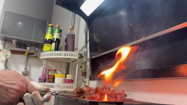 Glowing charcoal embers inside a small Chinese-style home charcoal grill, with hot coals and small flames heating a tabletop barbecue setup in a kitchen environment.