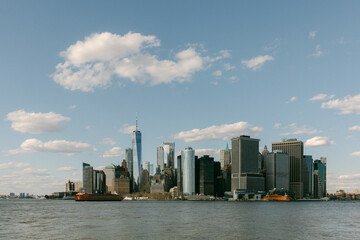 Obraz premium View of Lower Manhattan skyline with boats in the water on a sunny day with clouds in the sky