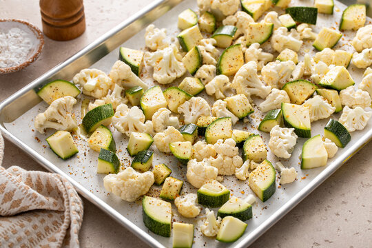 Fresh cauliflower and zucchini chopped on a baking sheet ready to be roasted