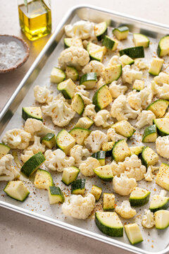 Fresh cauliflower and zucchini chopped on a baking sheet ready to be roasted