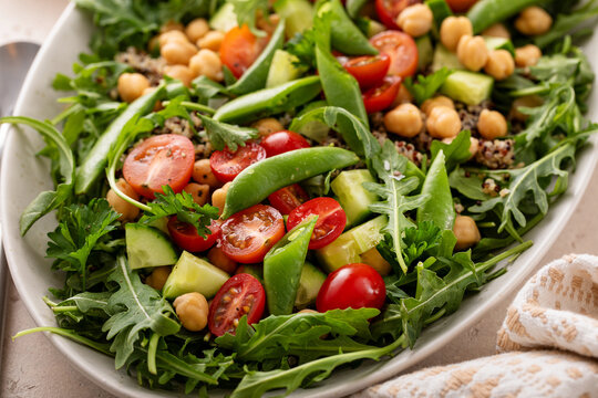 Fresh vegetables and quinoa salad with chickpeas, arugula and fresh peas with avocado ranch dressing