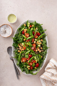 Fresh vegetables and quinoa salad with chickpeas, arugula and fresh peas with avocado ranch dressing