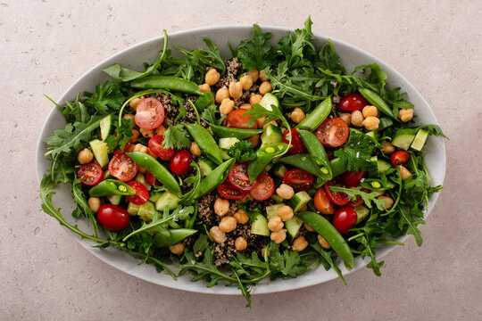 Fresh vegetables and quinoa salad with chickpeas, arugula and fresh peas with avocado ranch dressing