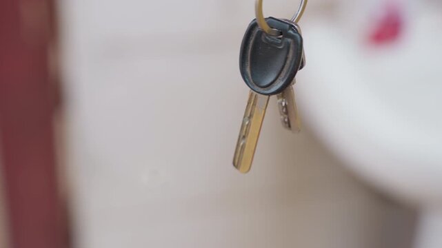 Technician examines keys at sink. Household service technician reviews key and fob for repairs. Professional maintenance specialist inspects house keys and fob before starting repairs