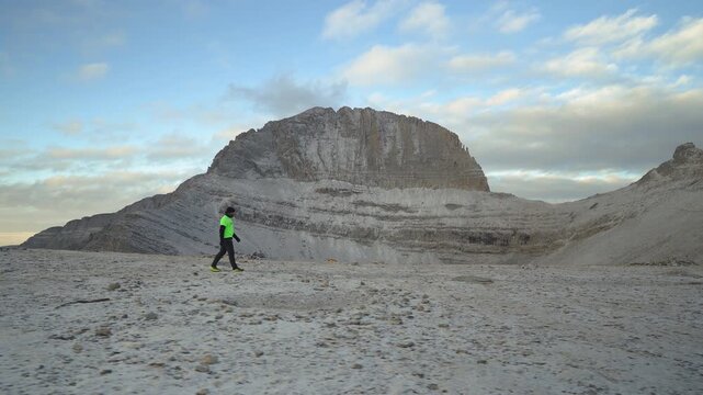 A lone man walks across the Plateau of the Muses on Mount Olympus at sunrise, with fresh snow and the Throne of Zeus, Mytikas peak in the background