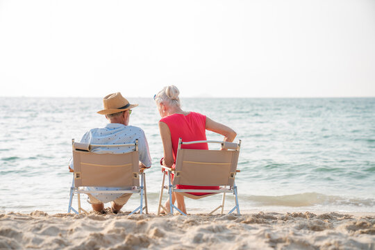 Happy senior couple sitting on a chair on the shore of the beach