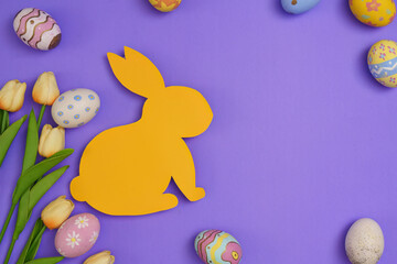 Fototapeta premium Easter Bunny. Yellow bunny silhouette surrounded by colorful eggs on a purple background.
