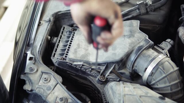Mechanic screw the air filter plastic cover after change of air filter in car repair garage