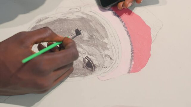 Black artist painting pink hat accent on portrait, closeup of hand and brush blending vibrant pigment, smooth texture on paper, playful finish under studio light enhancing saturation