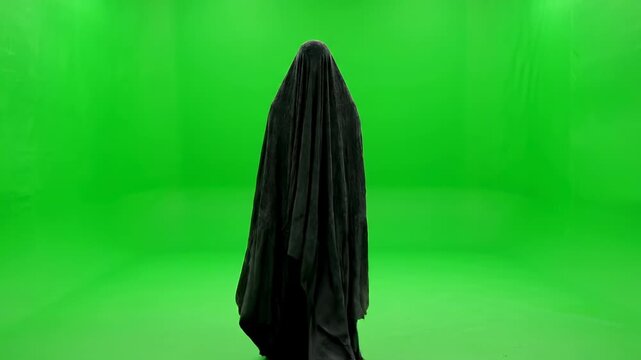 A draped, unseen figure slowly moving towards the camera on green screen horror, creepy, foreshadowing