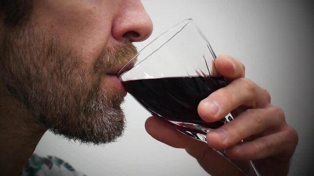 A man tasting red wine in a glass
