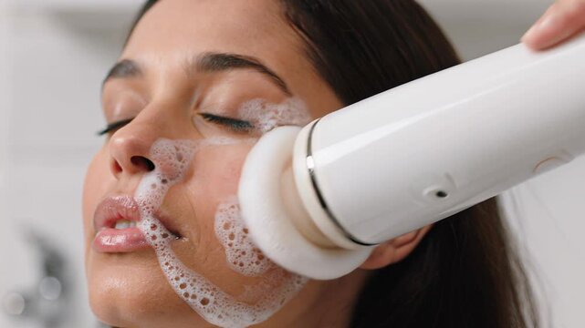 Beautiful woman cleaning her face with an electric sonic foaming brush
