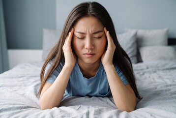 Fototapeta premium Young east asian woman suffering from headache in bed