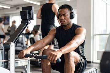 Fototapeta premium Man training on a rowing machine in a gym