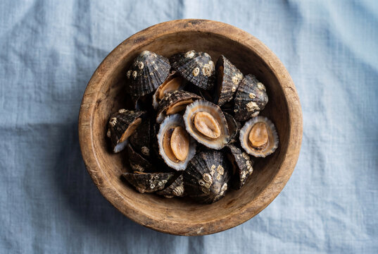 Authentic fresh lapas limpets in a rustic wooden bowl on a grey cloth