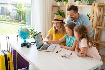 Fototapeta premium Happy family with two children planning summer vacation using laptop and looking at map on screen