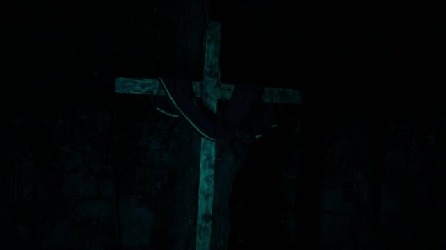 Wooden cross with cloth illuminated by changing lights at night