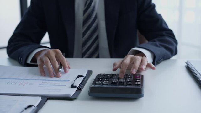 Accountant in suit do accounting and pressing calculator