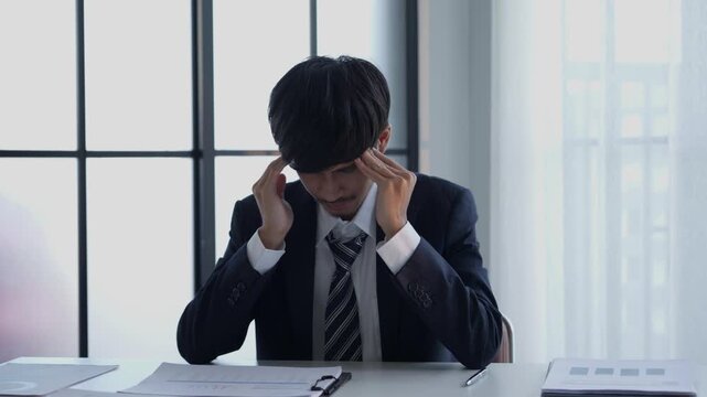 Stressed businessman holding head hard working in office