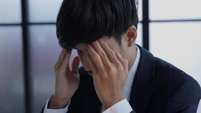 Stressed businessman holding head hard working in office