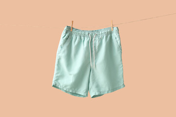 Swimming trunks hanging on clothesline against beige background