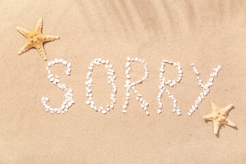 Word SORRY made of pebbles with starfishes on sand © Pixel-Shot