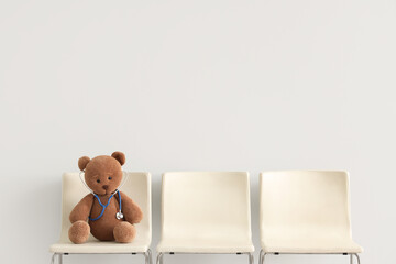 Toy bear with stethoscope on chair against light background. Concept of pediatrics