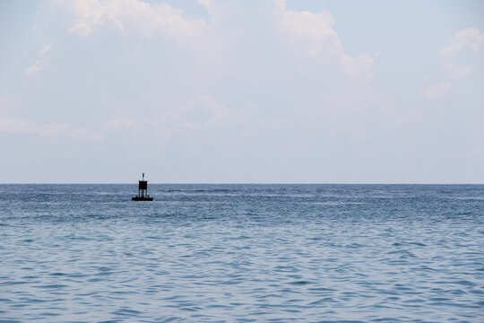Small navigation buoy in vast ocean with calm waters