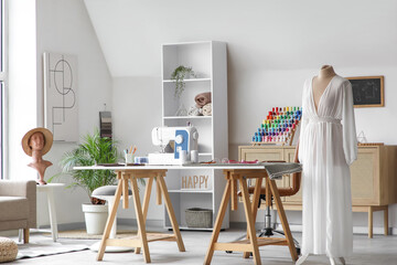 Interior of modern atelier with tailor's workplace, mannequin and shelf unit